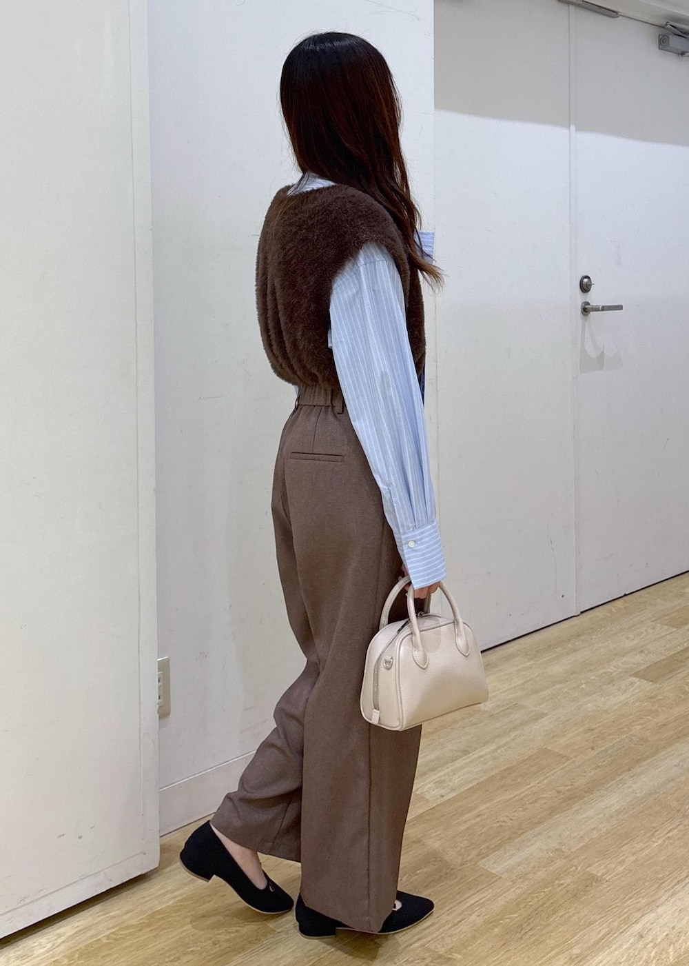 ブルー系のシャツ/ブラウス、ブラウン系のベスト、ベージュ系のスラックスを着用したレディースの秋コーディネートの3枚目の写真