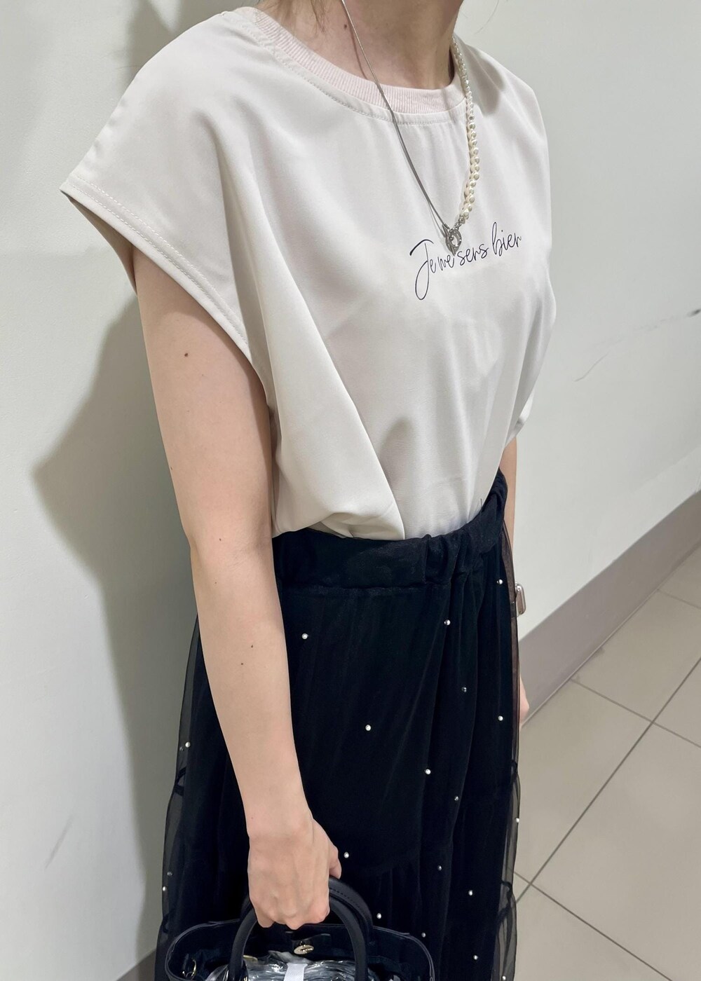 ブラック系のサンダル、ブラック系のショルダーバッグ、ベージュ系のTシャツ/カットソーを着用したレディースの夏コーディネートの5枚目の写真
