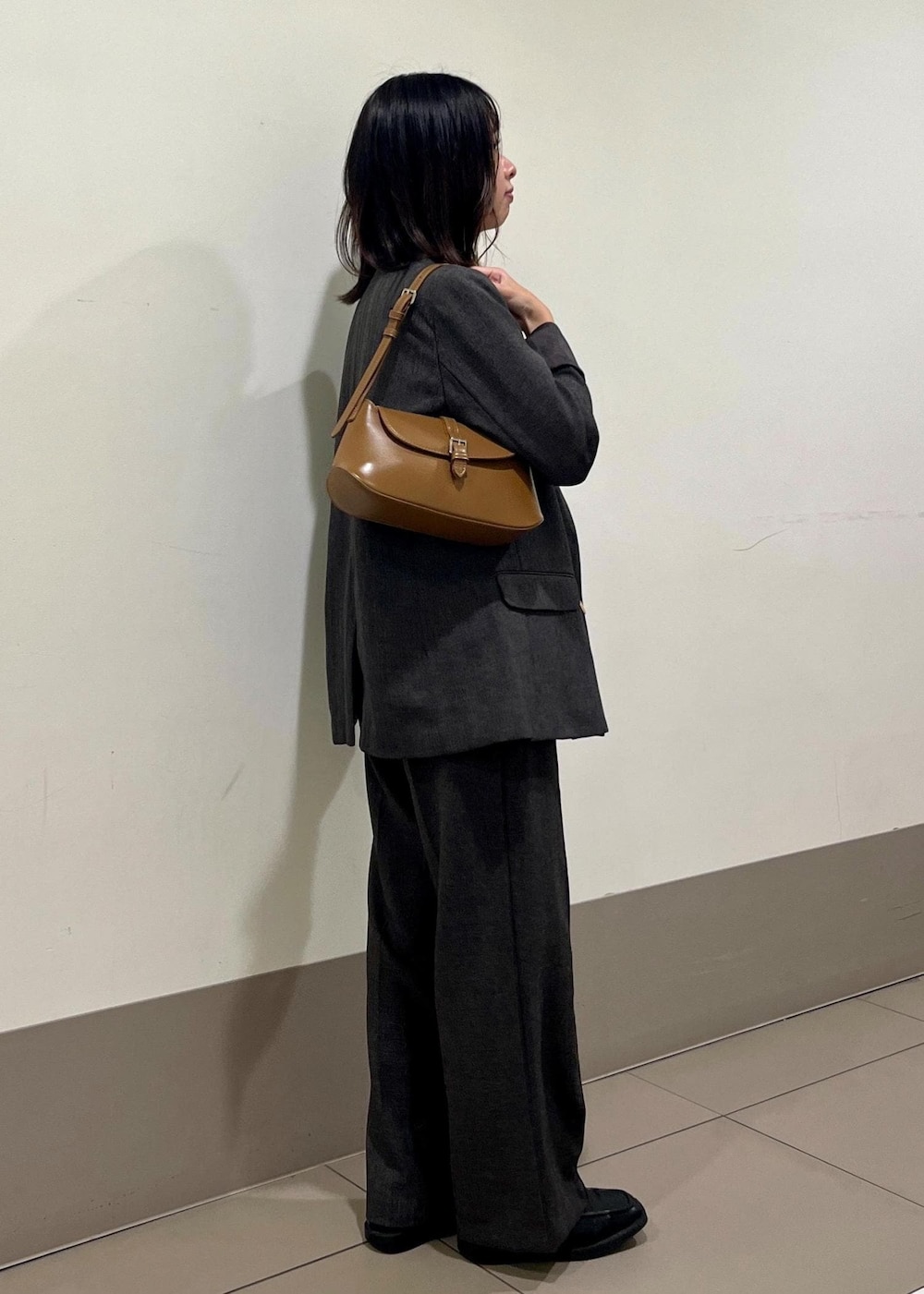 ブラック系のニット/セーター、ブラウン系のテーラードジャケット、ブラウン系のショルダーバッグを着用したレディースの秋コーディネートの3枚目の写真