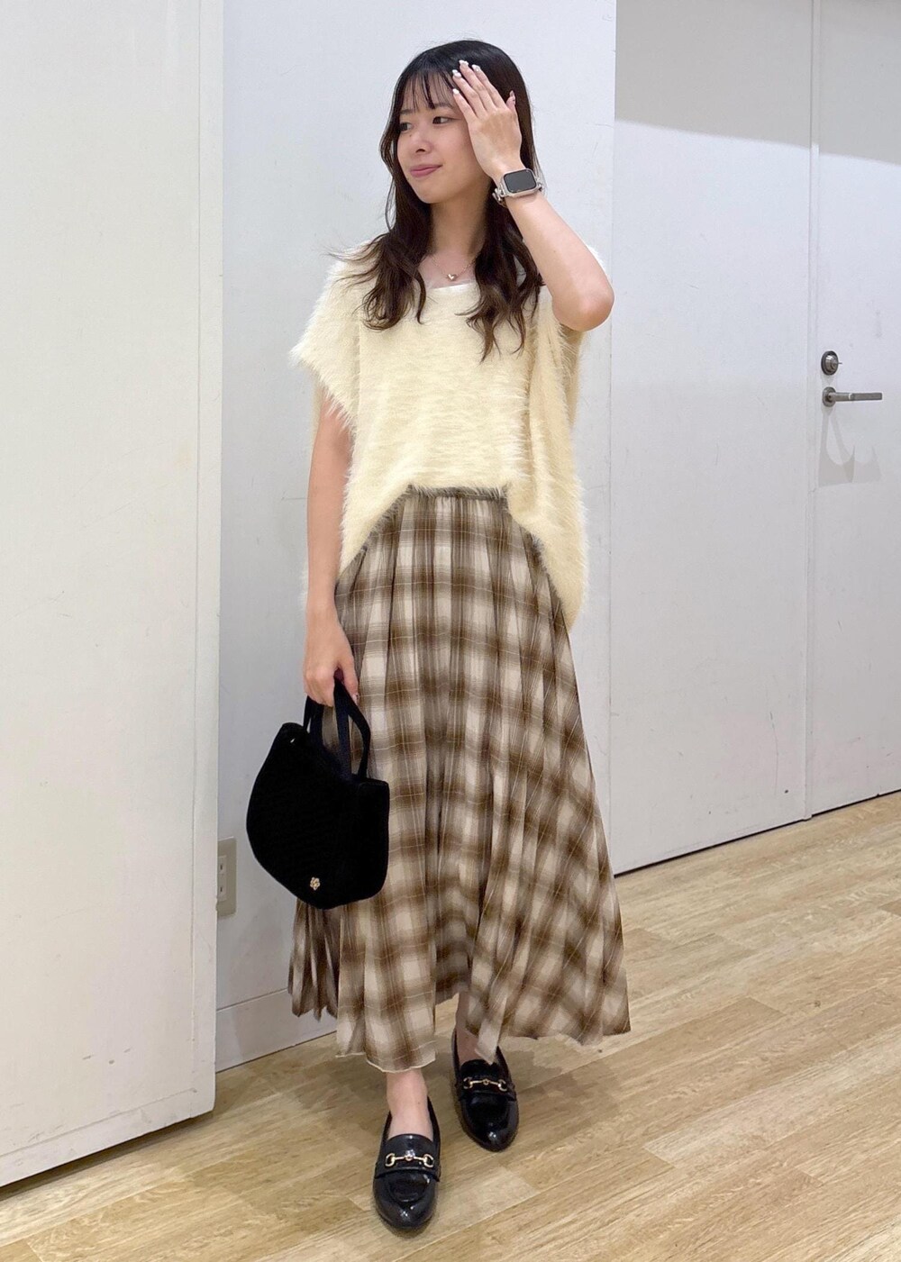 ホワイト系のタンクトップ、ホワイト系のベスト、イエロー系のスカートを着用したレディースの秋コーディネートの2枚目の写真