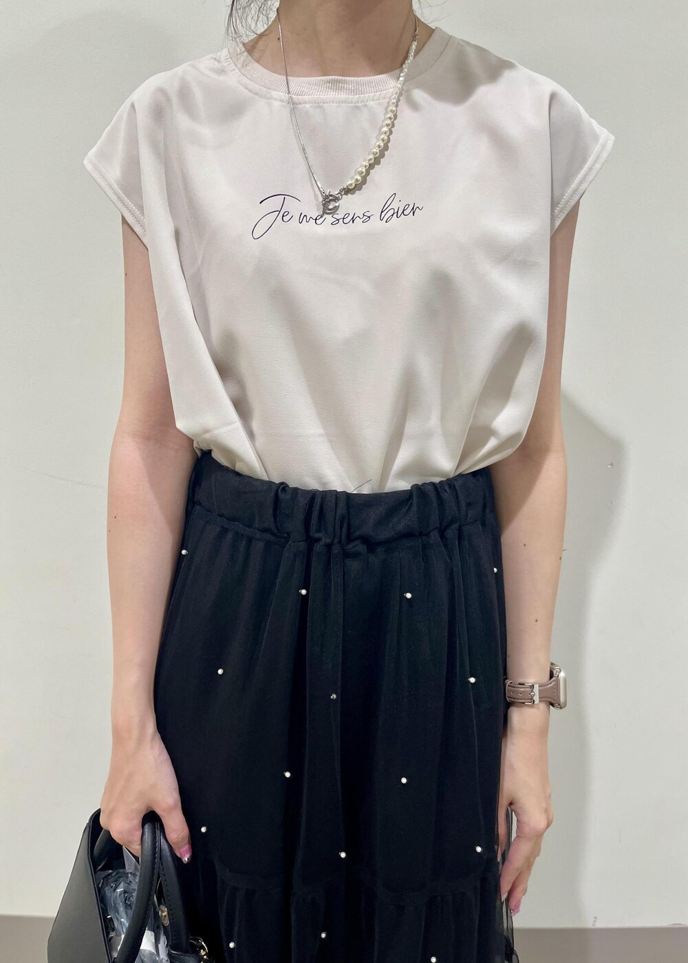 ブラック系のサンダル、ブラック系のショルダーバッグ、ベージュ系のTシャツ/カットソーを着用したレディースの夏コーディネートの4枚目の写真