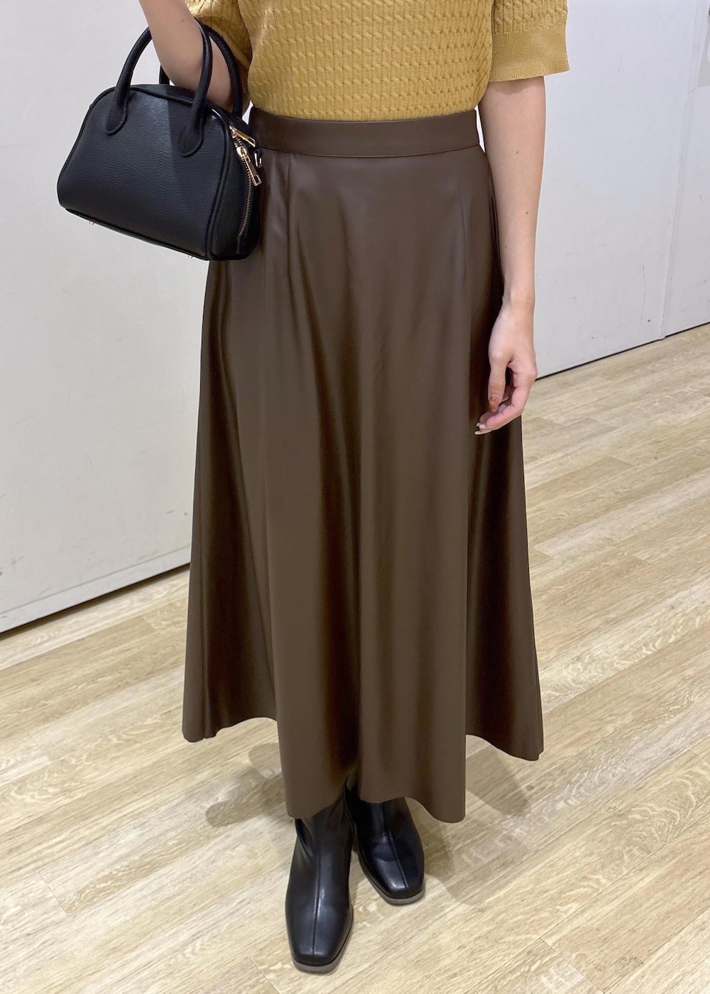 ブラウン系のスカート、イエロー系のポロシャツ、ブラック系のショルダーバッグを着用したレディースの秋コーディネートの7枚目の写真