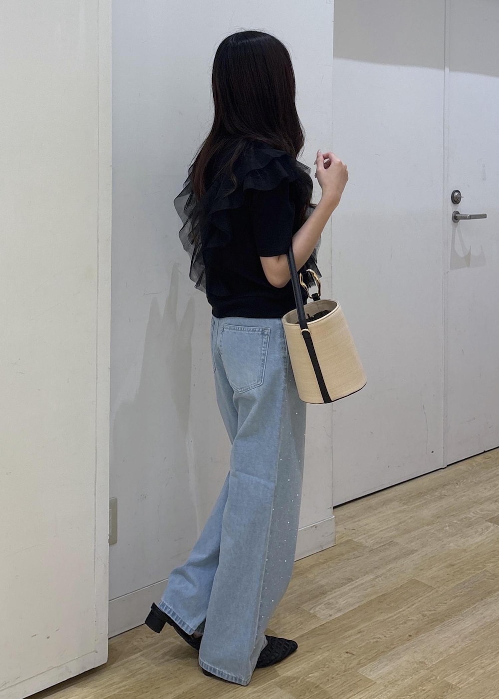 ブルー系のデニムパンツ、ブラック系のサンダル、ブラック系のハンドバッグを着用したレディースの春コーディネートの3枚目の写真