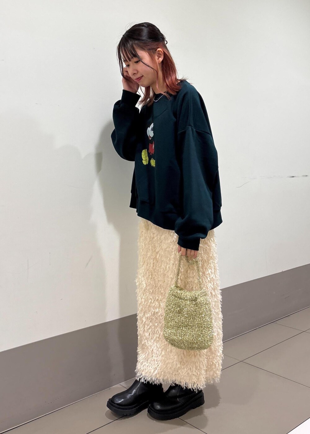 ホワイト系のスカート、ゴールド系のショルダーバッグ、グリーン系のスウェットを着用したレディースの冬コーディネートの3枚目の写真