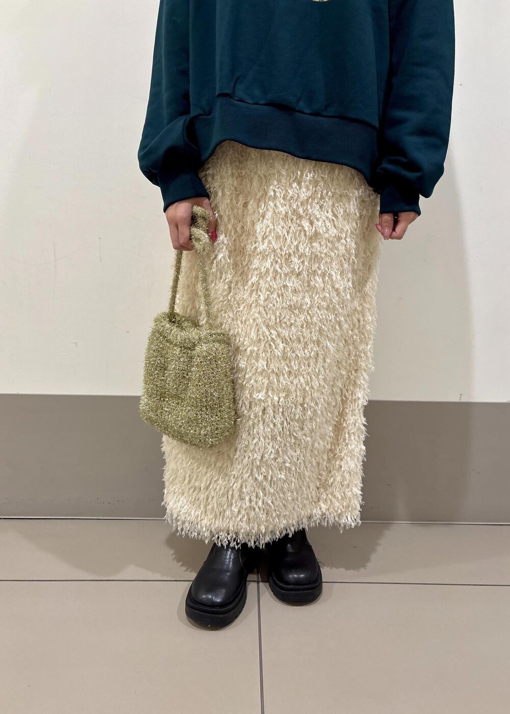 ホワイト系のスカート、ゴールド系のショルダーバッグ、グリーン系のスウェットを着用したレディースの冬コーディネートの6枚目の写真