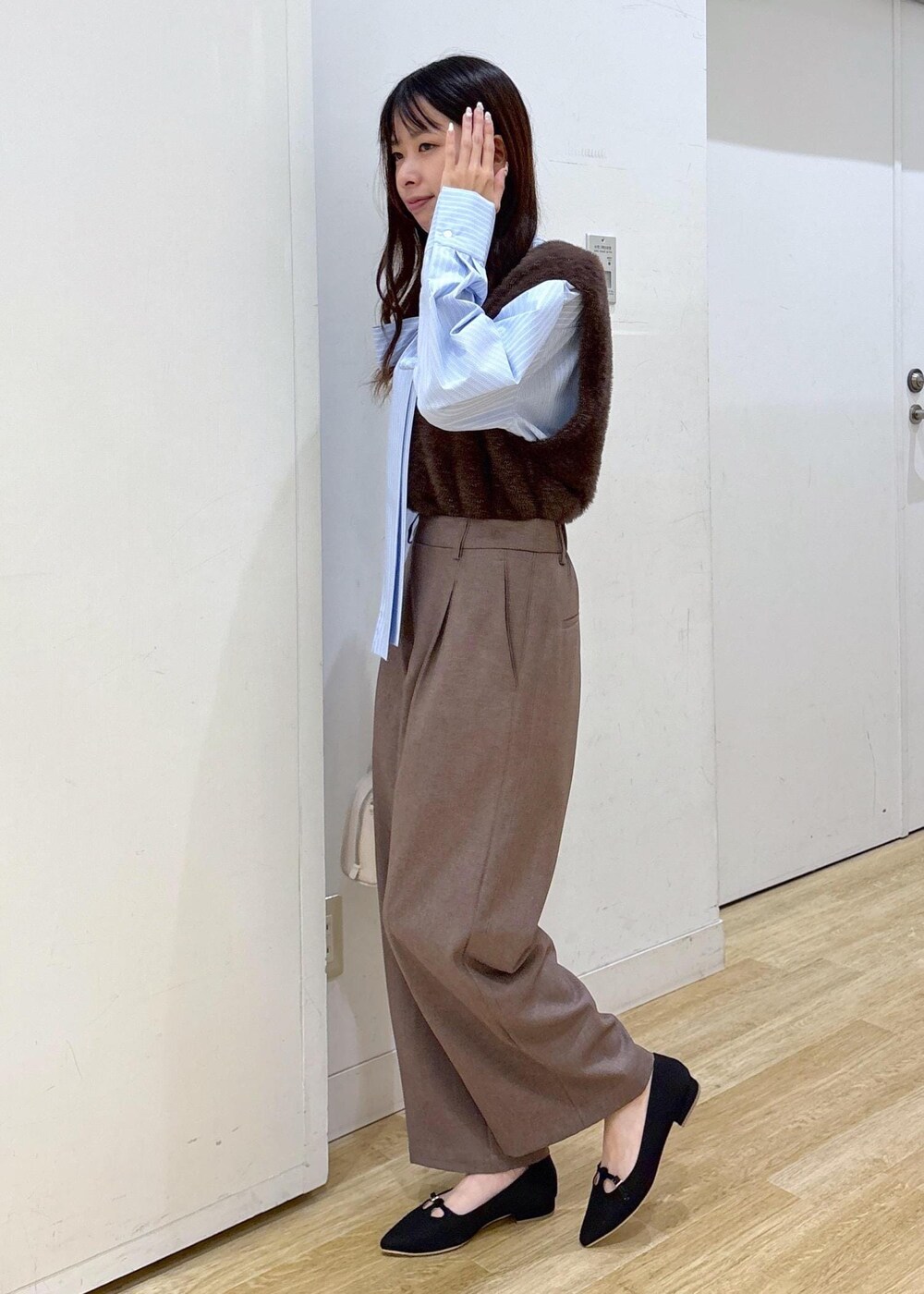 ブルー系のシャツ/ブラウス、ブラウン系のベスト、ベージュ系のスラックスを着用したレディースの秋コーディネートの5枚目の写真
