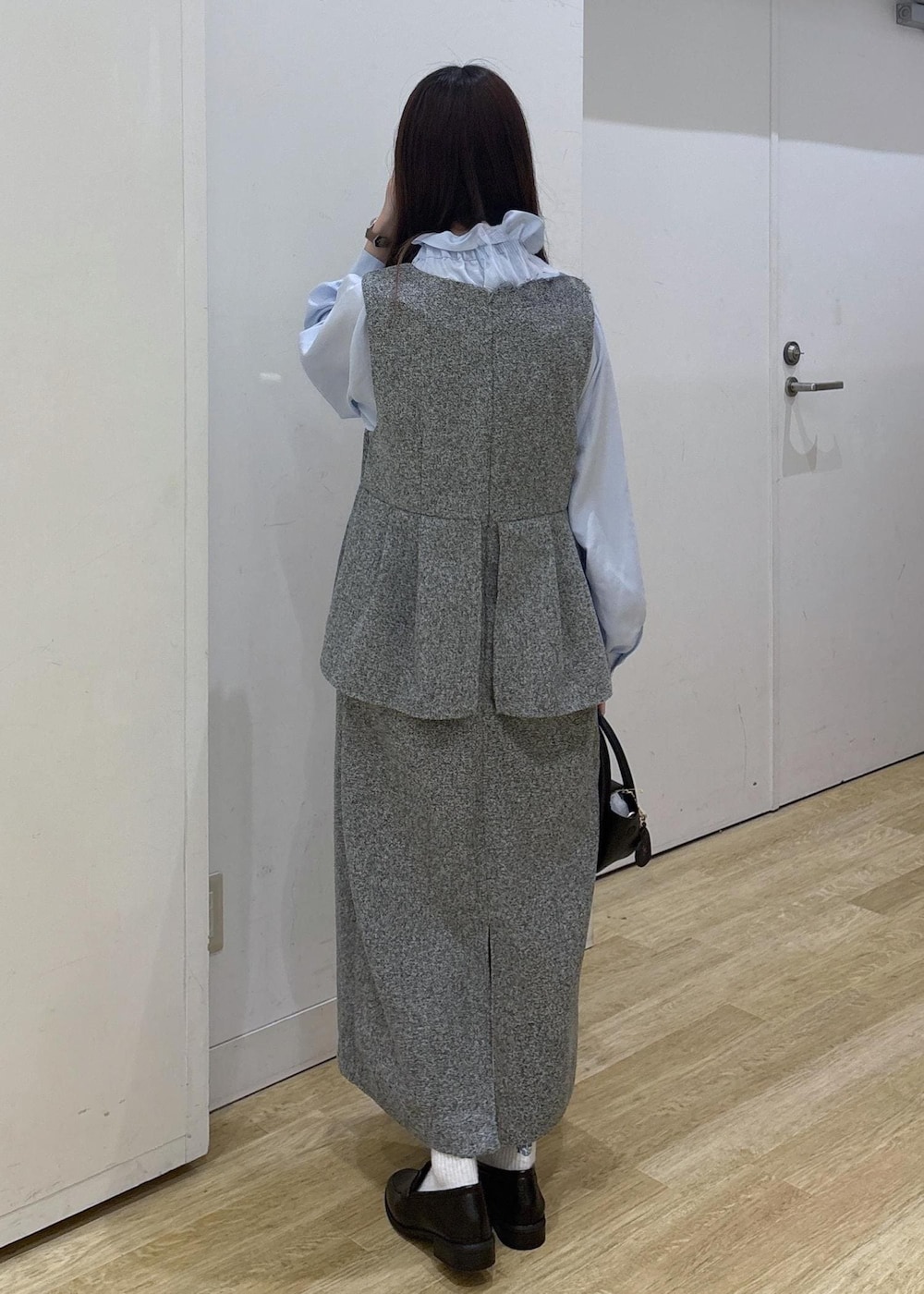 ブラック系のショルダーバッグ、ブラック系のローファー、グレー系のジャンパースカートを着用したレディースの冬コーディネートの4枚目の写真