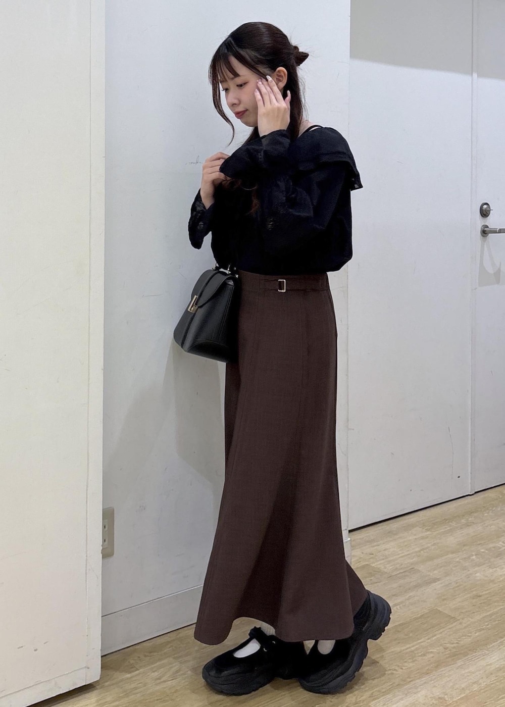 ブラック系のショルダーバッグ、ブラウン系のスカート、ブラック系のシャツ/ブラウスを着用したレディースの春コーディネートの3枚目の写真