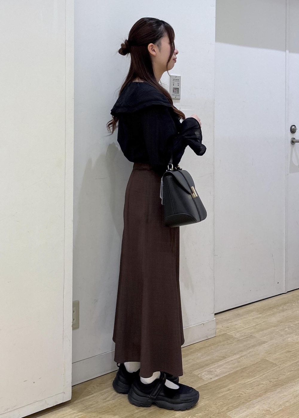 ブラック系のショルダーバッグ、ブラウン系のスカート、ブラック系のシャツ/ブラウスを着用したレディースの春コーディネートの5枚目の写真