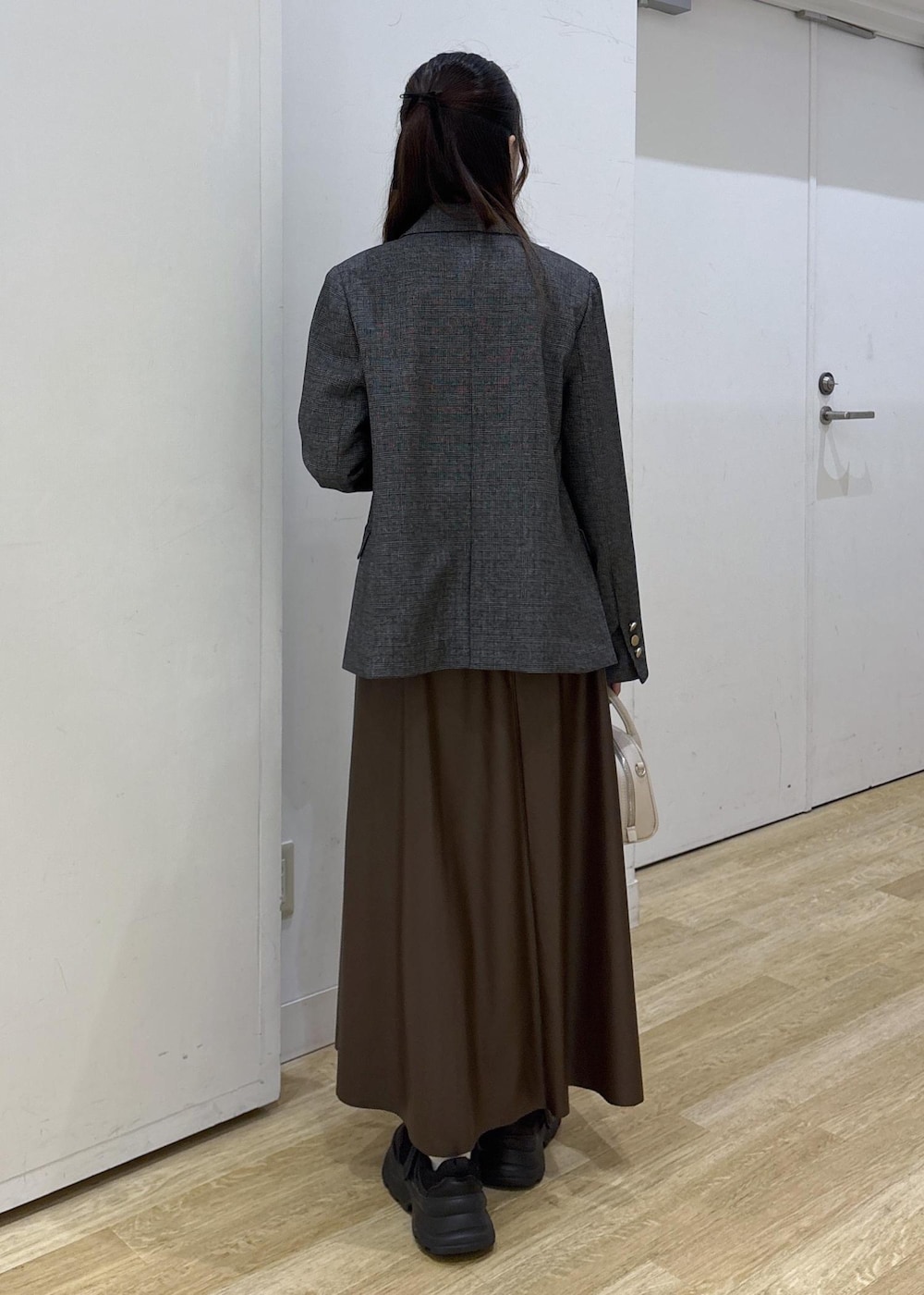 グレー系のテーラードジャケット、ホワイト系のTシャツ/カットソー、ブラウン系のスカートを着用したレディースの秋コーディネートの4枚目の写真