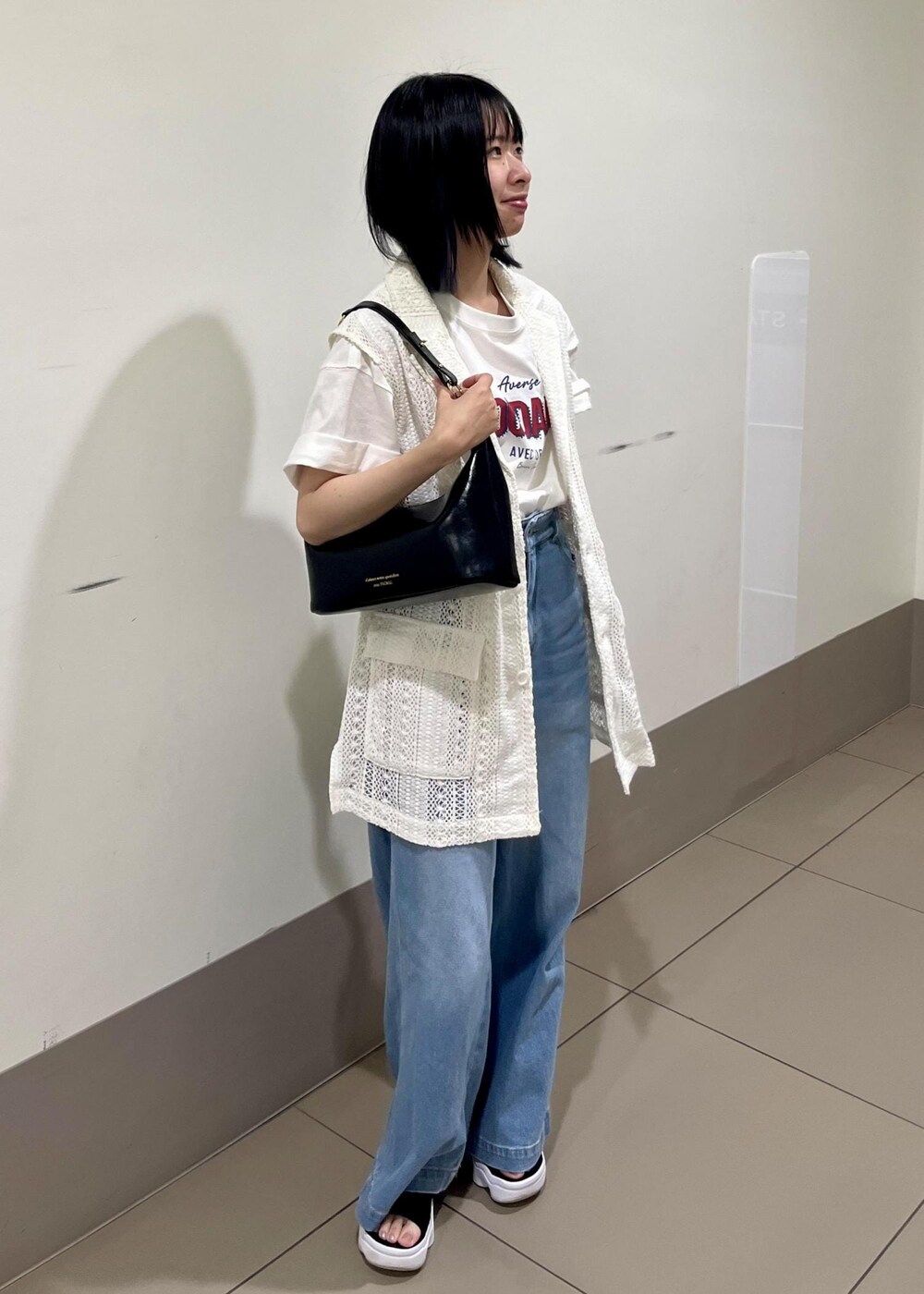 ブラック系のショルダーバッグ、ブルー系のデニムパンツ、ホワイト系のTシャツ/カットソーを着用したレディースの夏コーディネートの2枚目の写真