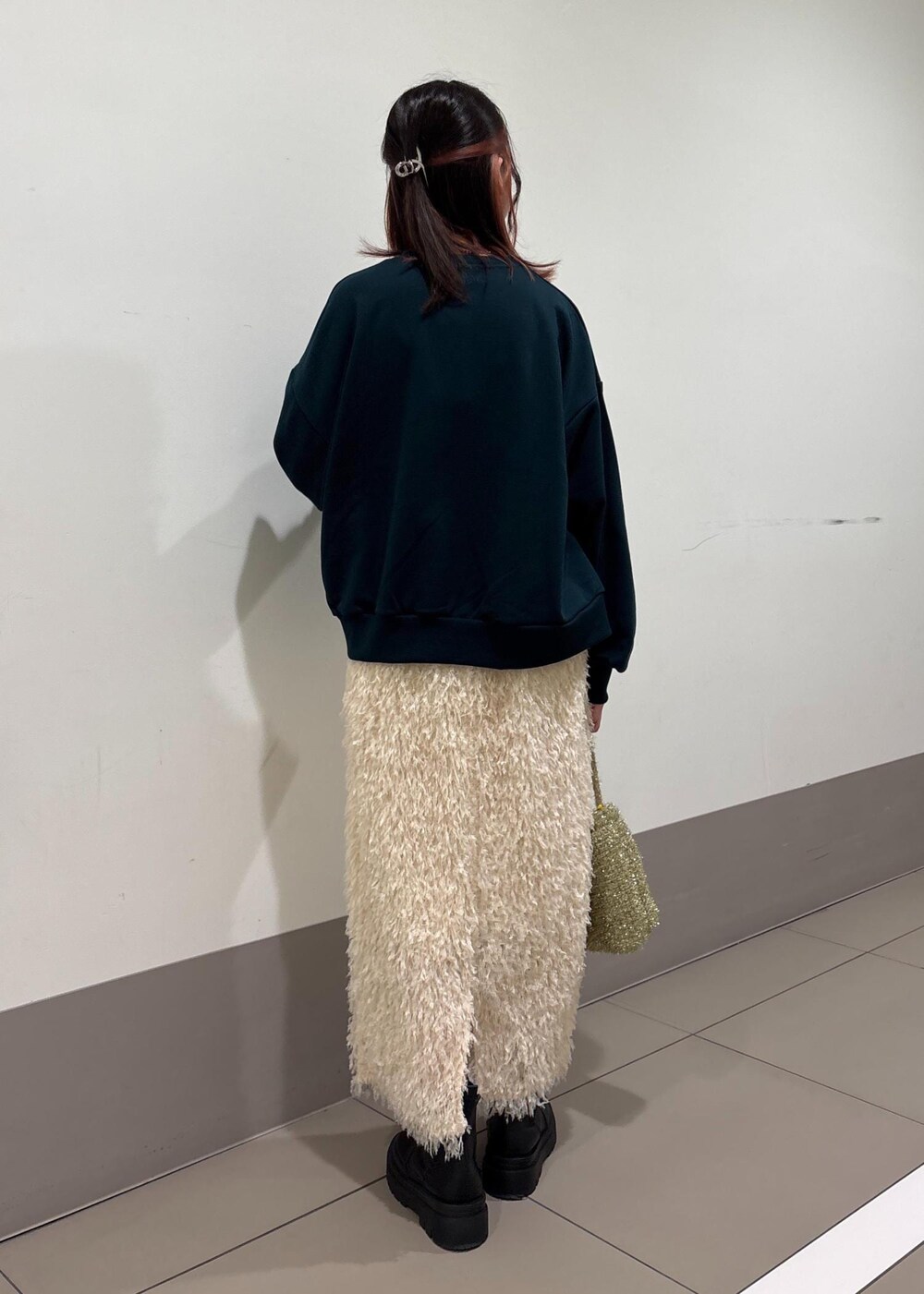 ホワイト系のスカート、ゴールド系のショルダーバッグ、グリーン系のスウェットを着用したレディースの冬コーディネートの4枚目の写真