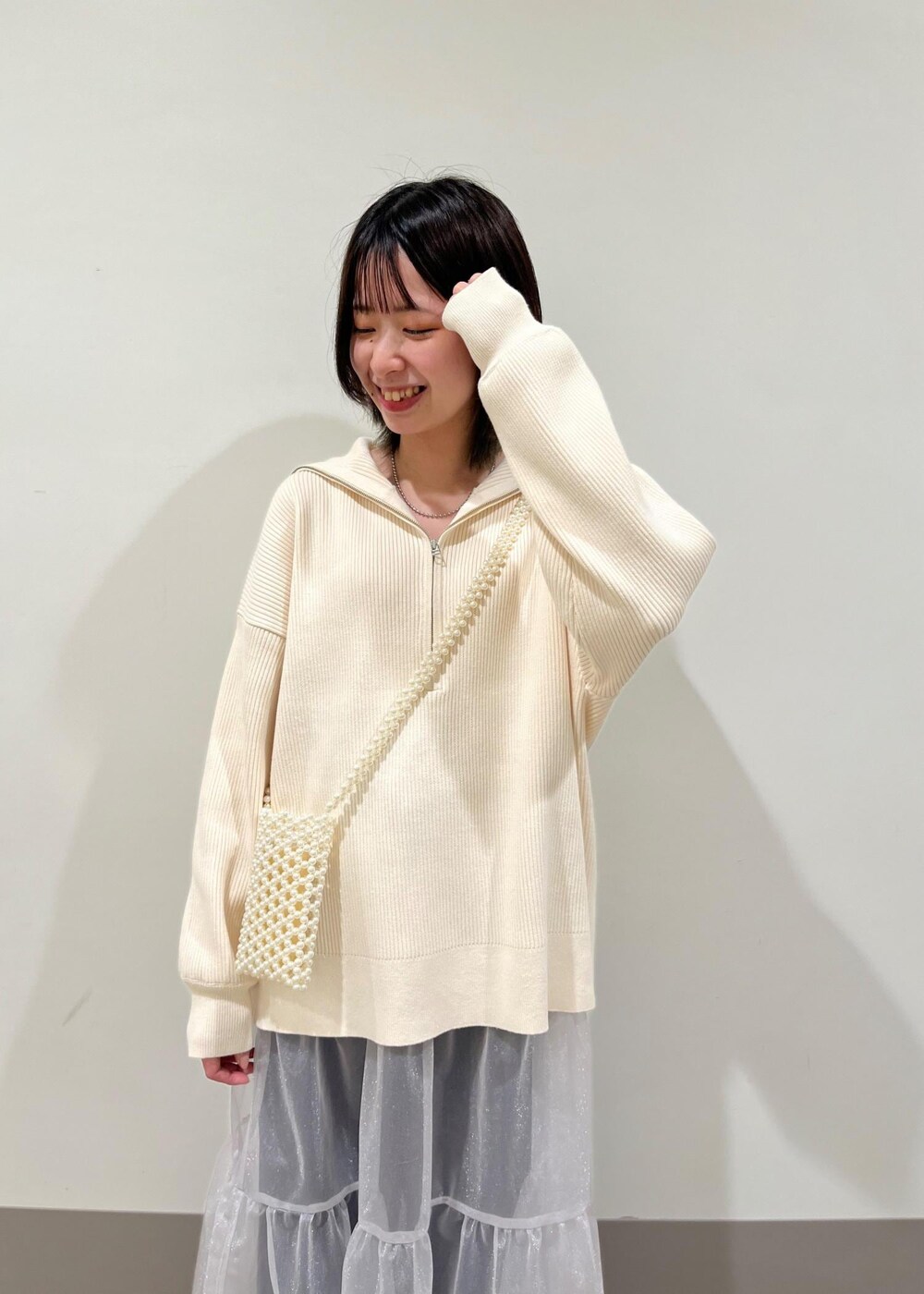 ホワイト系のショルダーバッグ、ブルー系のデニムパンツ、グレー系のスカートを着用したレディースの春コーディネートの4枚目の写真