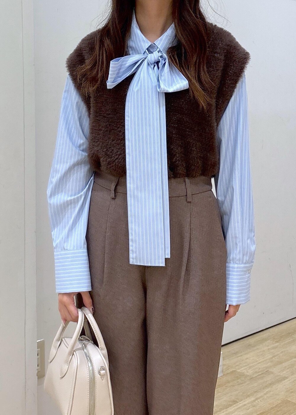 ブルー系のシャツ/ブラウス、ブラウン系のベスト、ベージュ系のスラックスを着用したレディースの秋コーディネートの6枚目の写真