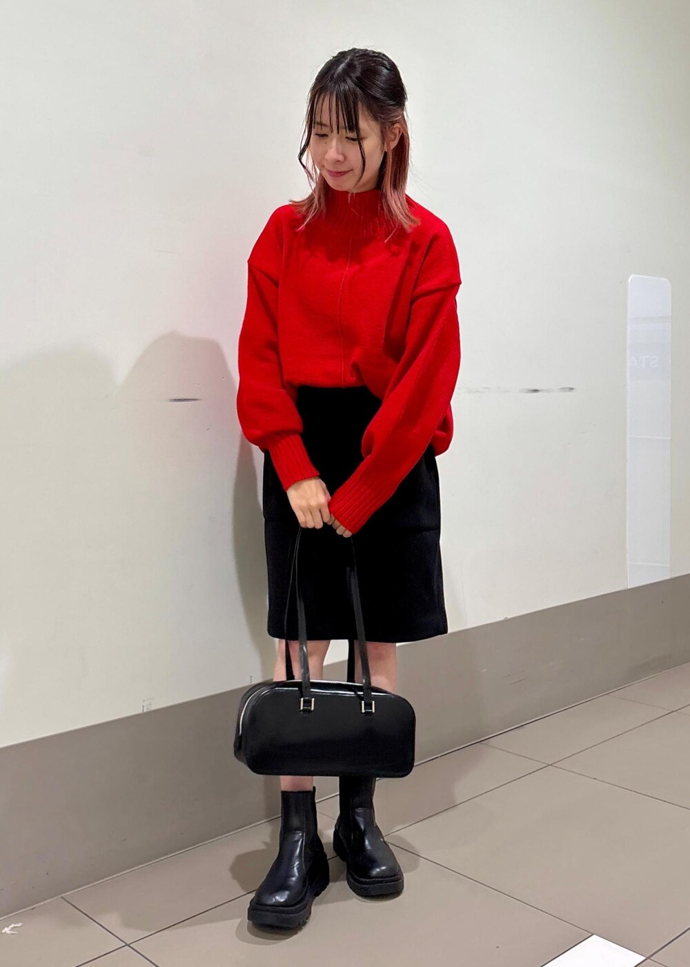 レッド系のニット/セーター、ブラック系のボストンバッグ、ブラック系のスカートを着用したレディースの冬コーディネートの4枚目の写真