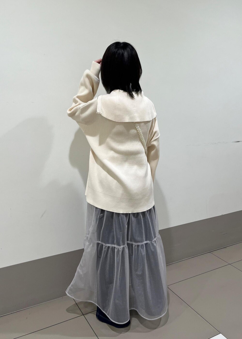 ホワイト系のショルダーバッグ、ブルー系のデニムパンツ、グレー系のスカートを着用したレディースの春コーディネートの2枚目の写真