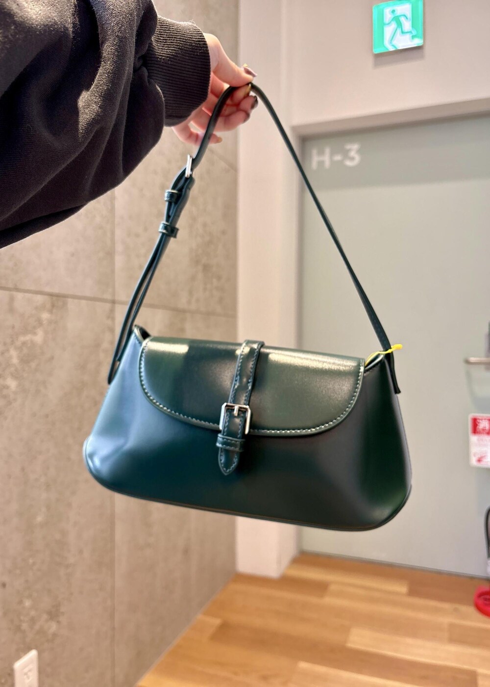 グリーン系のショルダーバッグ、ブラック系のブーツ、グレー系のスカートを着用したレディースの冬コーディネートの5枚目の写真