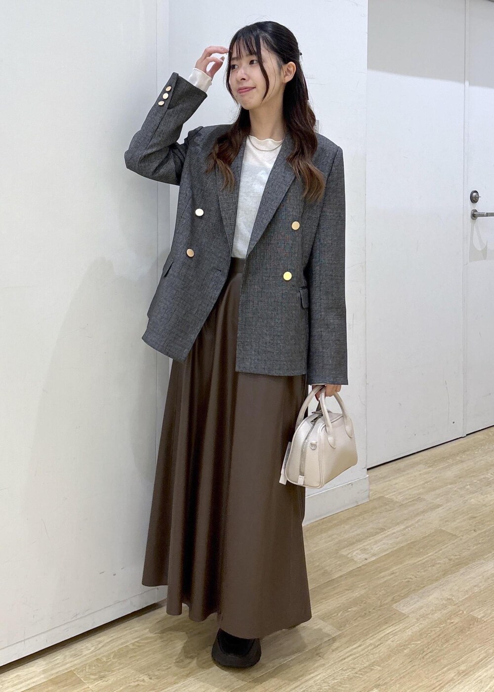 グレー系のテーラードジャケット、ホワイト系のTシャツ/カットソー、ブラウン系のスカートを着用したレディースの秋コーディネートの2枚目の写真