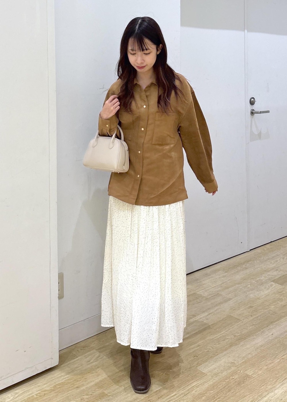 ホワイト系のスカート、ブラウン系のシャツ/ブラウス、ブラウン系のブーツを着用したレディースの秋コーディネートの2枚目の写真