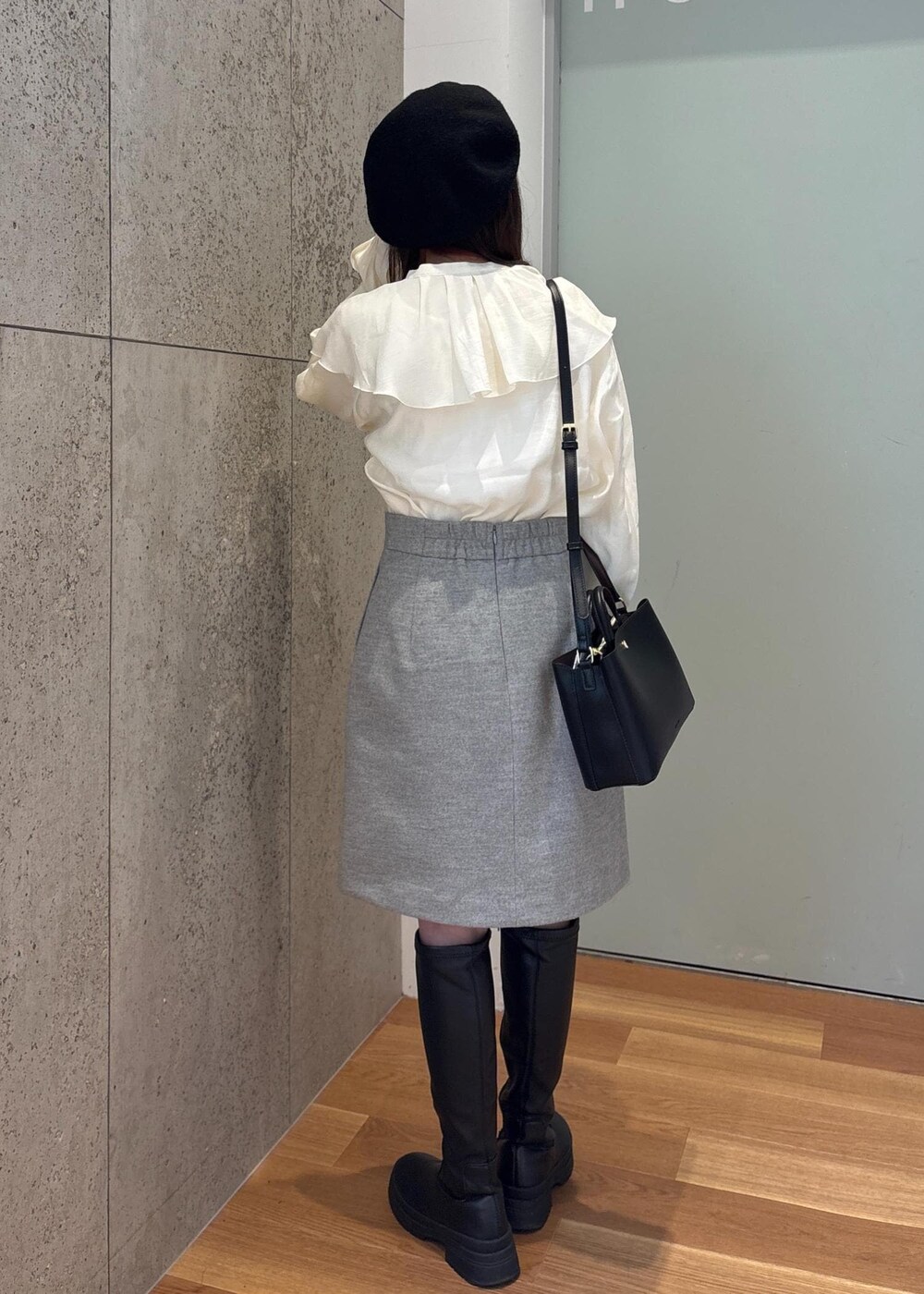 グレー系のスカート、ホワイト系のシャツ/ブラウス、ブラック系のブーツを着用したレディースの冬コーディネートの3枚目の写真