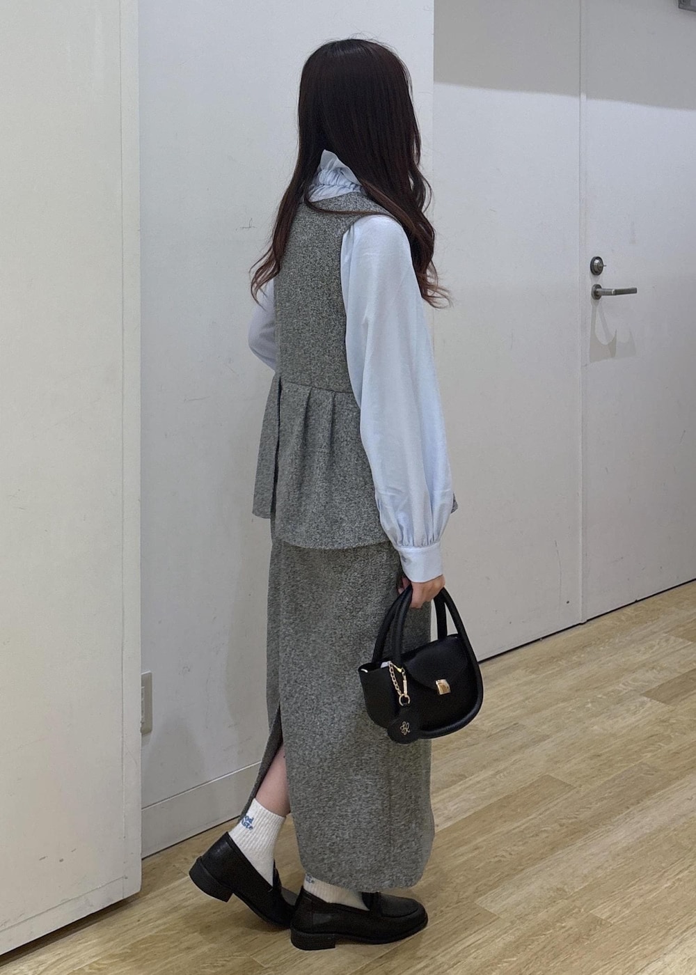 ブラック系のショルダーバッグ、ブラック系のローファー、グレー系のジャンパースカートを着用したレディースの冬コーディネートの3枚目の写真