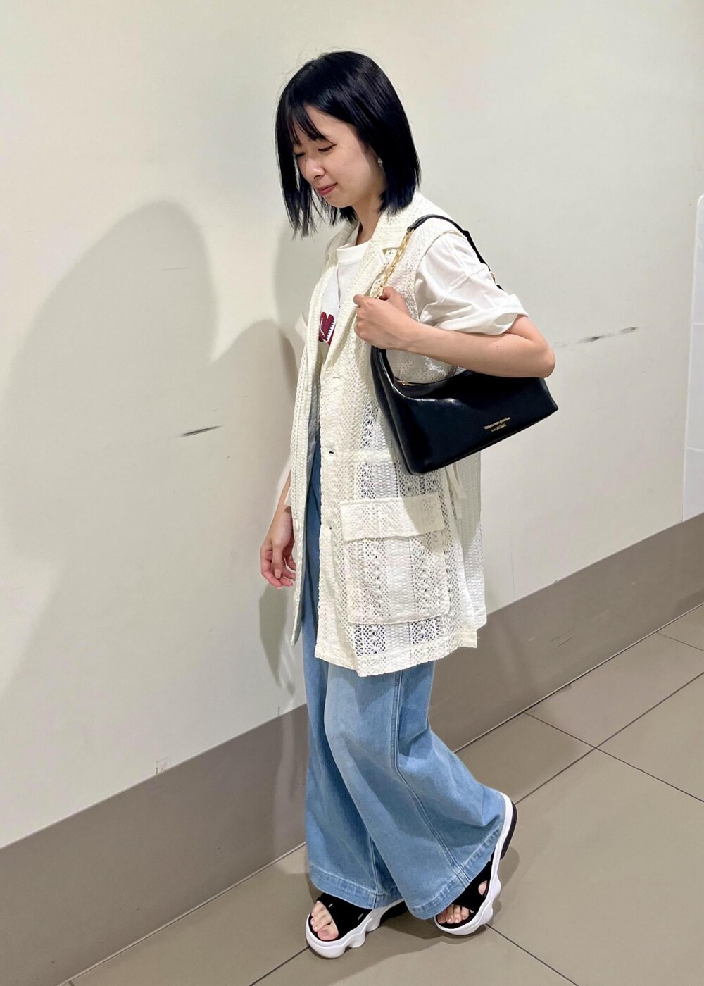 ブラック系のショルダーバッグ、ブルー系のデニムパンツ、ホワイト系のTシャツ/カットソーを着用したレディースの夏コーディネートの4枚目の写真