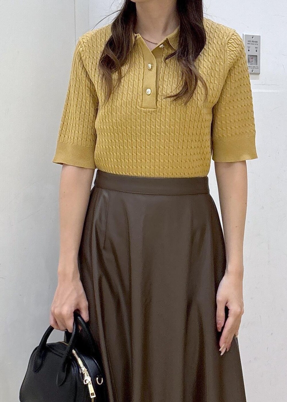 ブラウン系のスカート、イエロー系のポロシャツ、ブラック系のショルダーバッグを着用したレディースの秋コーディネートの6枚目の写真