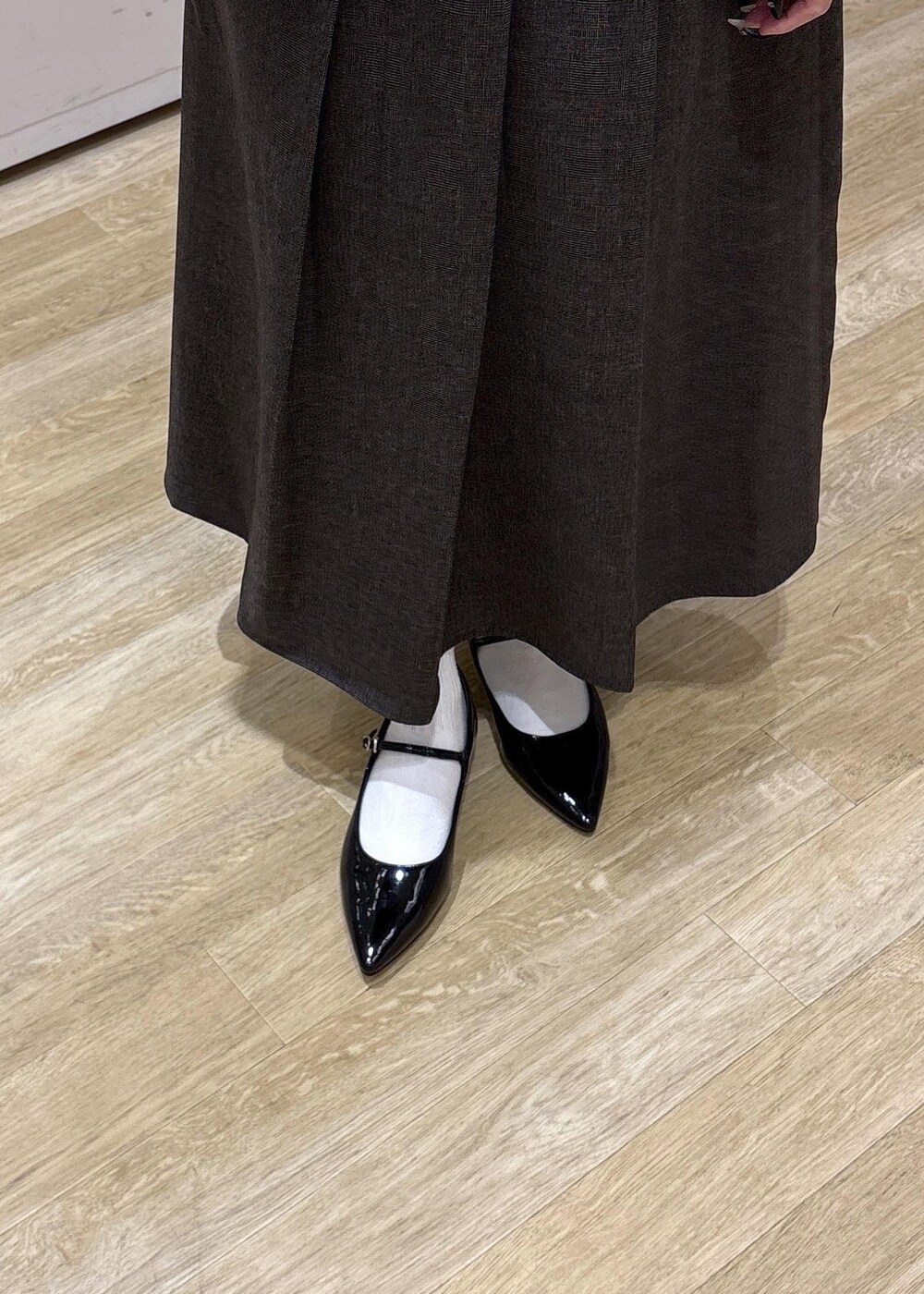 ブラック系のパンプス、ブラック系のトートバッグ、ブラウン系のスカートを着用したレディースの秋コーディネートの8枚目の写真