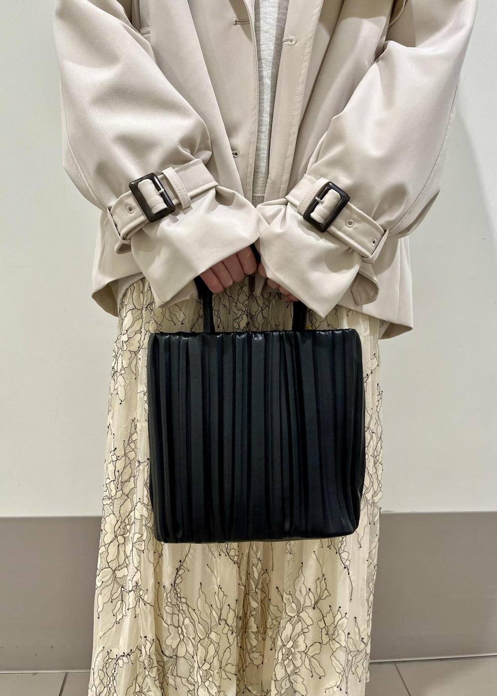 ブラック系のローファー、ホワイト系のスカート、ベージュ系のトレンチコートを着用したレディースの春コーディネートの6枚目の写真