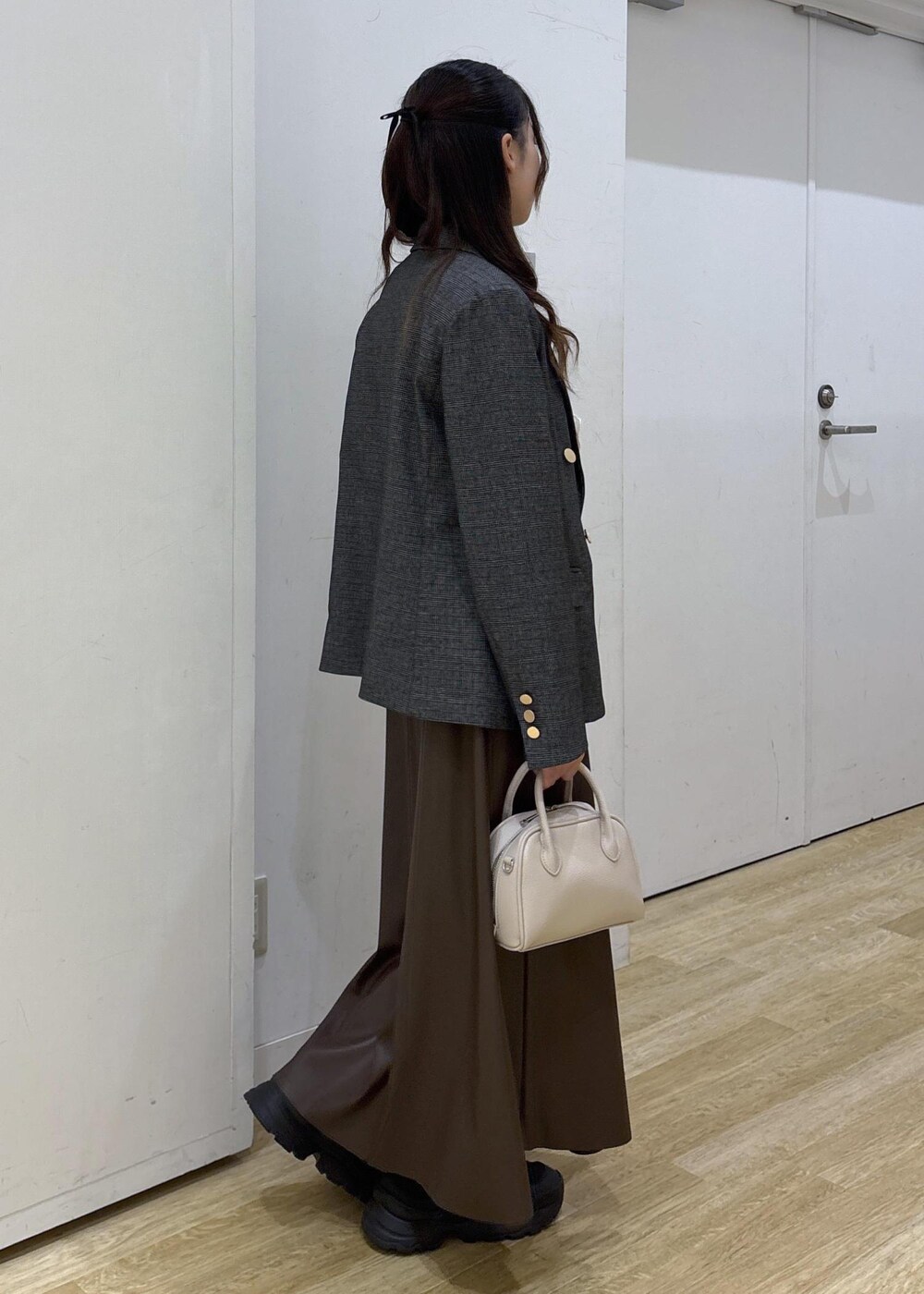グレー系のテーラードジャケット、ホワイト系のTシャツ/カットソー、ブラウン系のスカートを着用したレディースの秋コーディネートの5枚目の写真