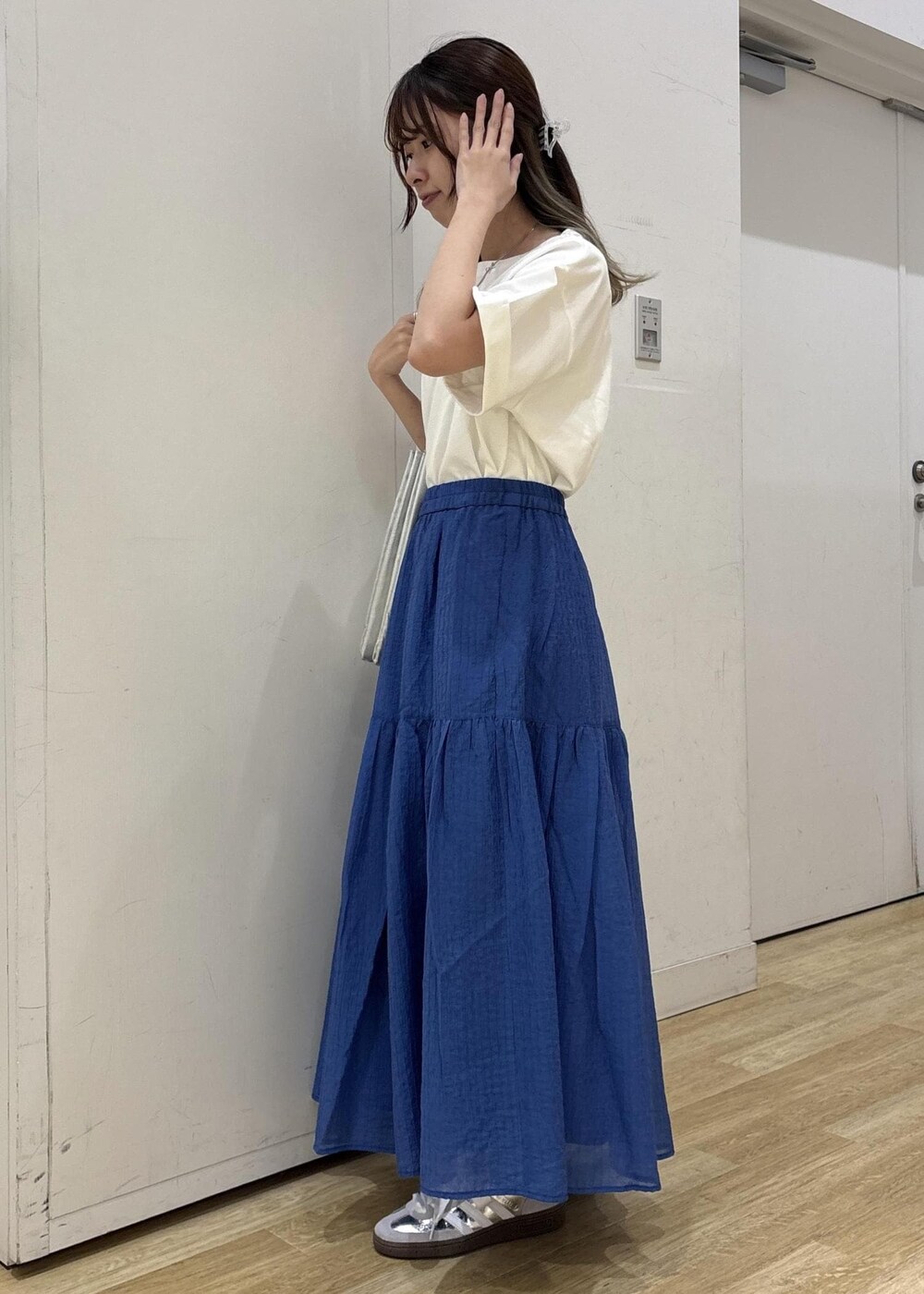 シルバー系のトートバッグ、ブルー系のスカート、ホワイト系のTシャツ/カットソーを着用したレディースの夏コーディネートの3枚目の写真