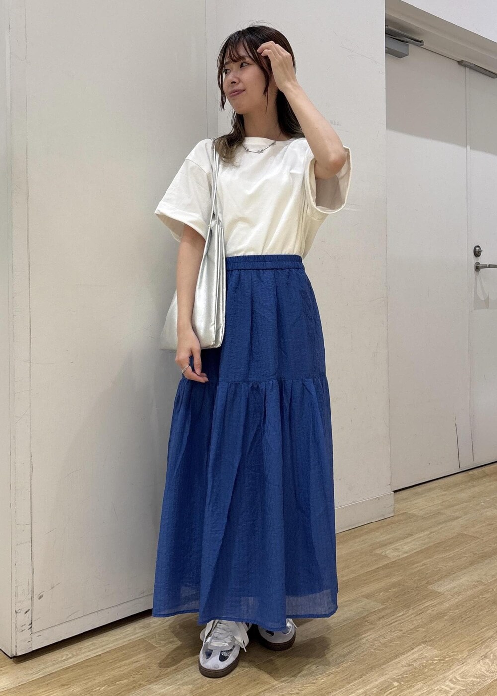 シルバー系のトートバッグ、ブルー系のスカート、ホワイト系のTシャツ/カットソーを着用したレディースの夏コーディネートの2枚目の写真