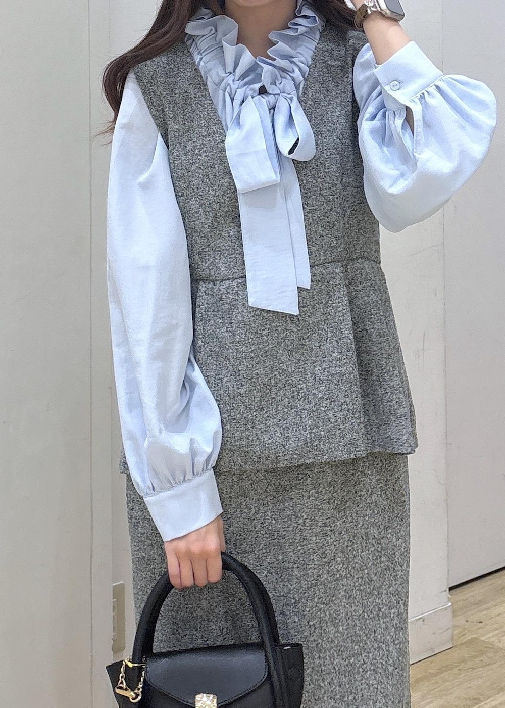 ブラック系のショルダーバッグ、ブラック系のローファー、グレー系のジャンパースカートを着用したレディースの冬コーディネートの5枚目の写真