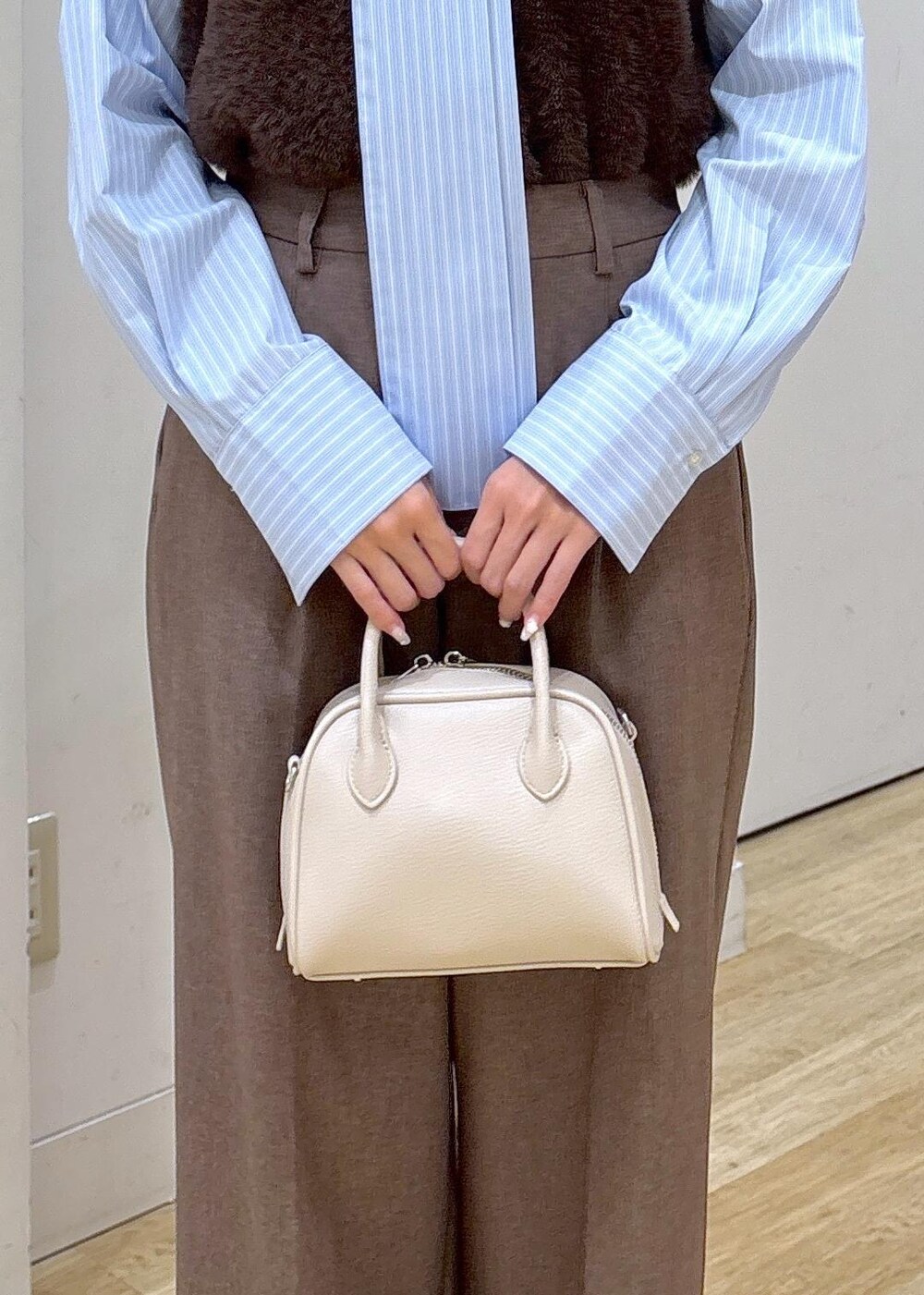 ブルー系のシャツ/ブラウス、ブラウン系のベスト、ベージュ系のスラックスを着用したレディースの秋コーディネートの7枚目の写真