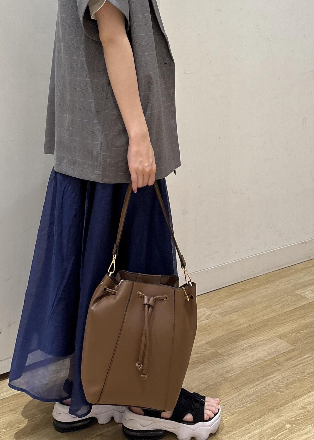 グレー系のテーラードジャケット、ブラウン系のショルダーバッグ、ブルー系のスカートを着用したレディースの夏コーディネートの7枚目の写真