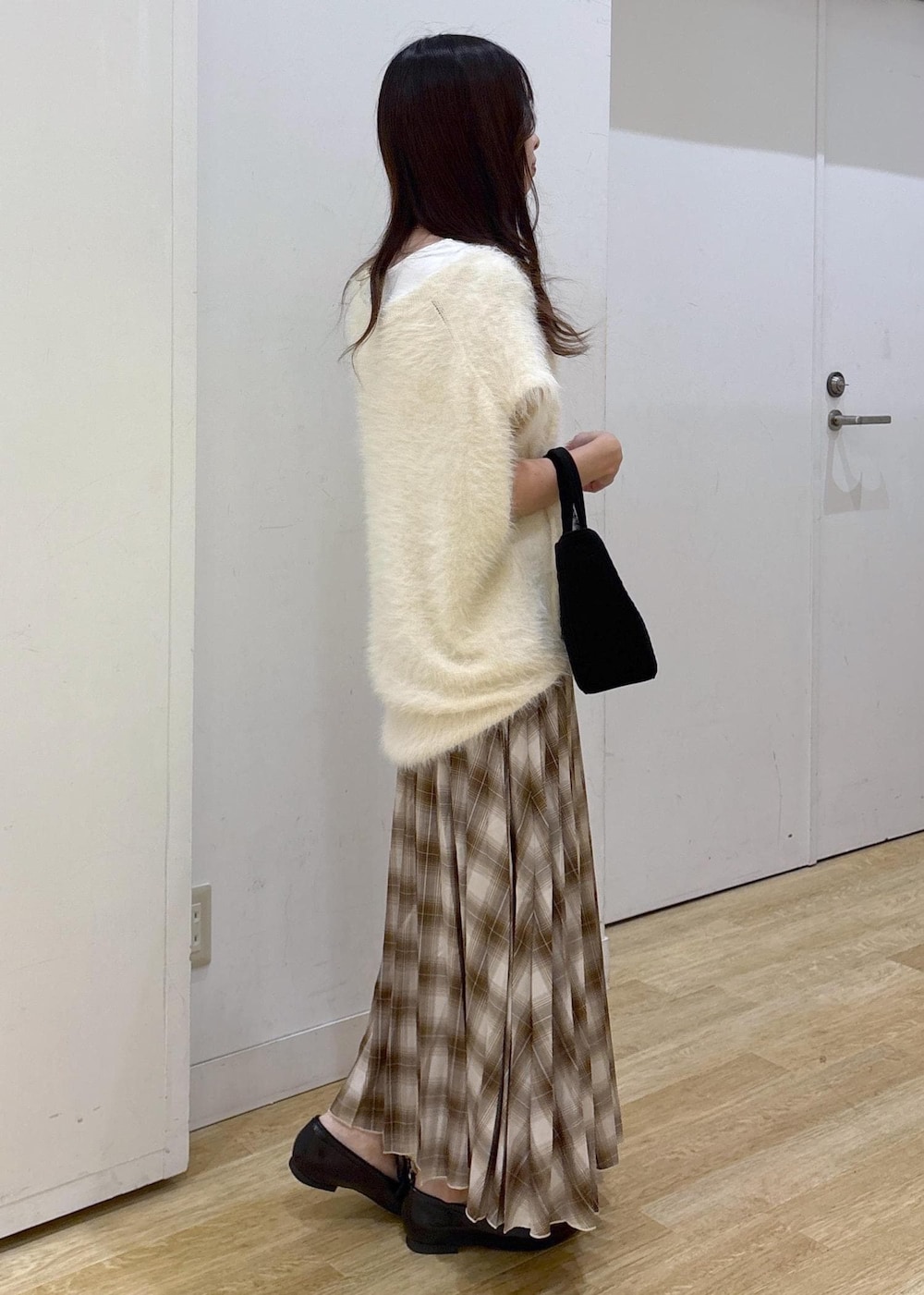 ホワイト系のタンクトップ、ホワイト系のベスト、イエロー系のスカートを着用したレディースの秋コーディネートの3枚目の写真