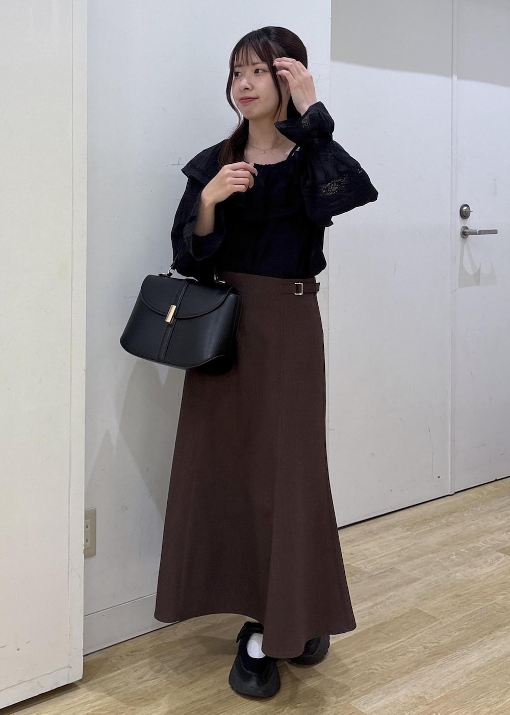 ブラック系のショルダーバッグ、ブラウン系のスカート、ブラック系のシャツ/ブラウスを着用したレディースの春コーディネートの2枚目の写真