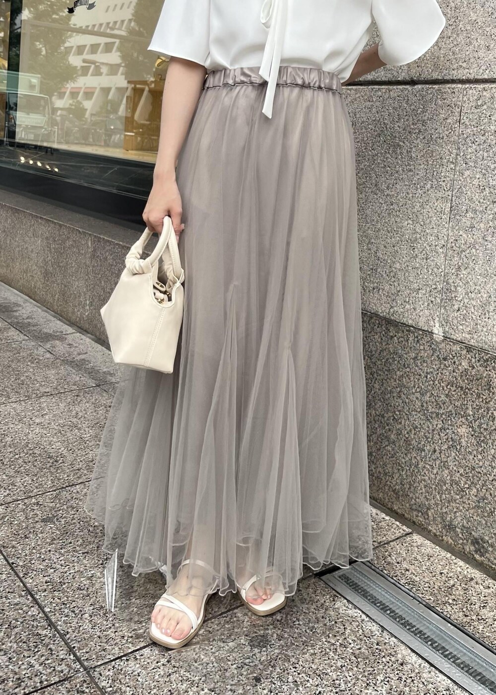 ベージュ系のスカート、ホワイト系のシャツ/ブラウス、ホワイト系のサンダルを着用したレディースの夏コーディネートの5枚目の写真