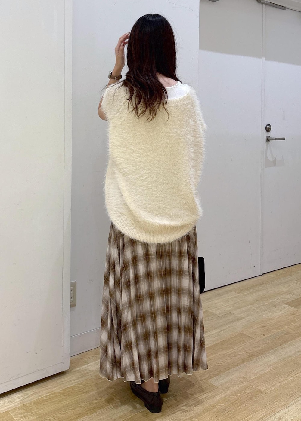 ホワイト系のタンクトップ、ホワイト系のベスト、イエロー系のスカートを着用したレディースの秋コーディネートの4枚目の写真