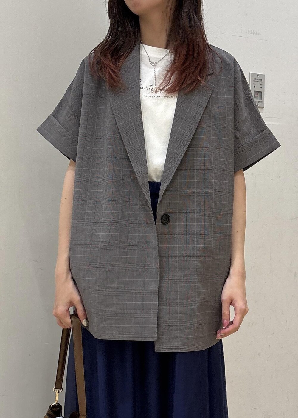 グレー系のテーラードジャケット、ブラウン系のショルダーバッグ、ブルー系のスカートを着用したレディースの夏コーディネートの6枚目の写真