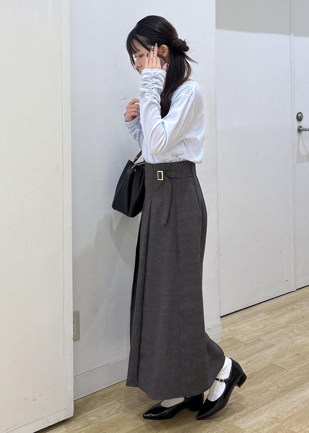 ブラック系のパンプス、ブラック系のトートバッグ、ブラウン系のスカートを着用したレディースの秋コーディネートの5枚目の写真