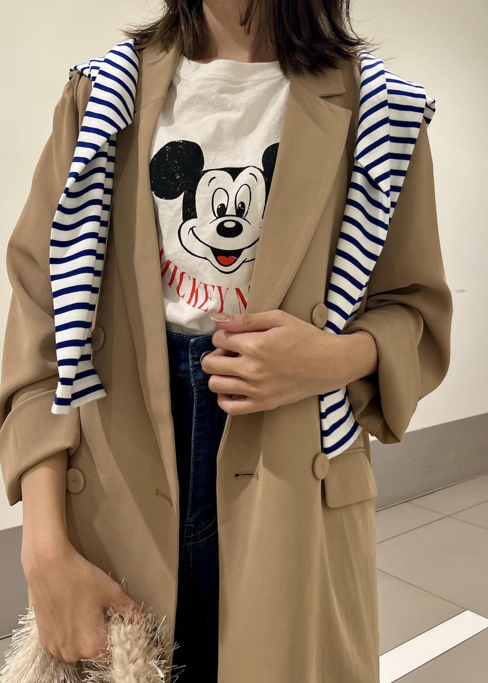 ブルー系のデニムパンツ、ベージュ系のハンドバッグ、ブルー系のTシャツ/カットソーを着用したレディースの秋コーディネートの4枚目の写真