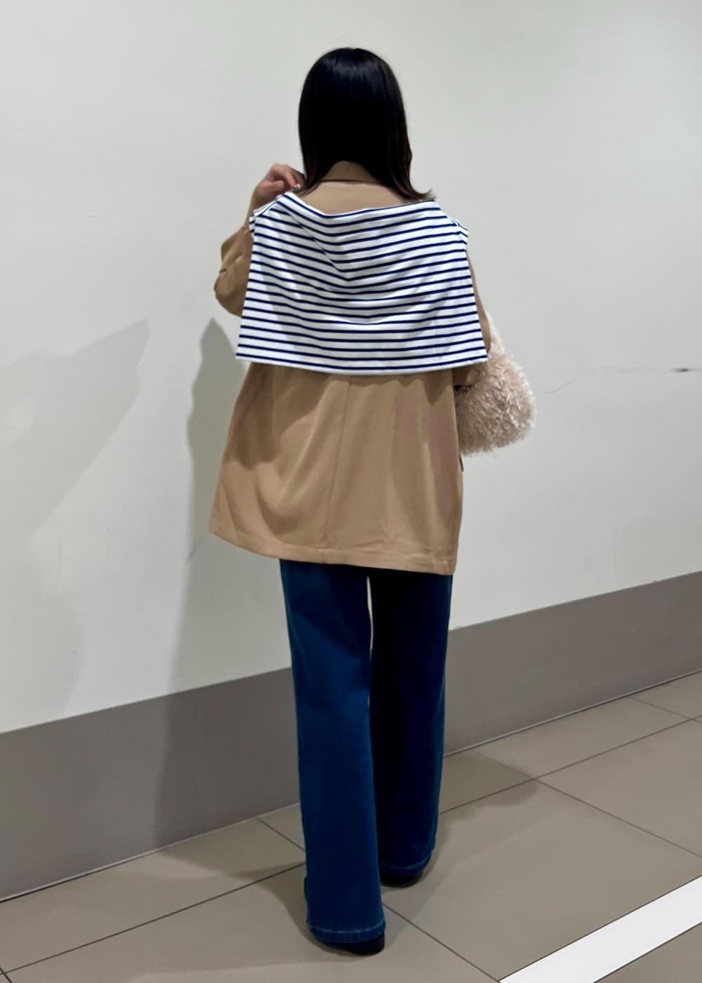 ブルー系のデニムパンツ、ベージュ系のハンドバッグ、ブルー系のTシャツ/カットソーを着用したレディースの秋コーディネートの3枚目の写真