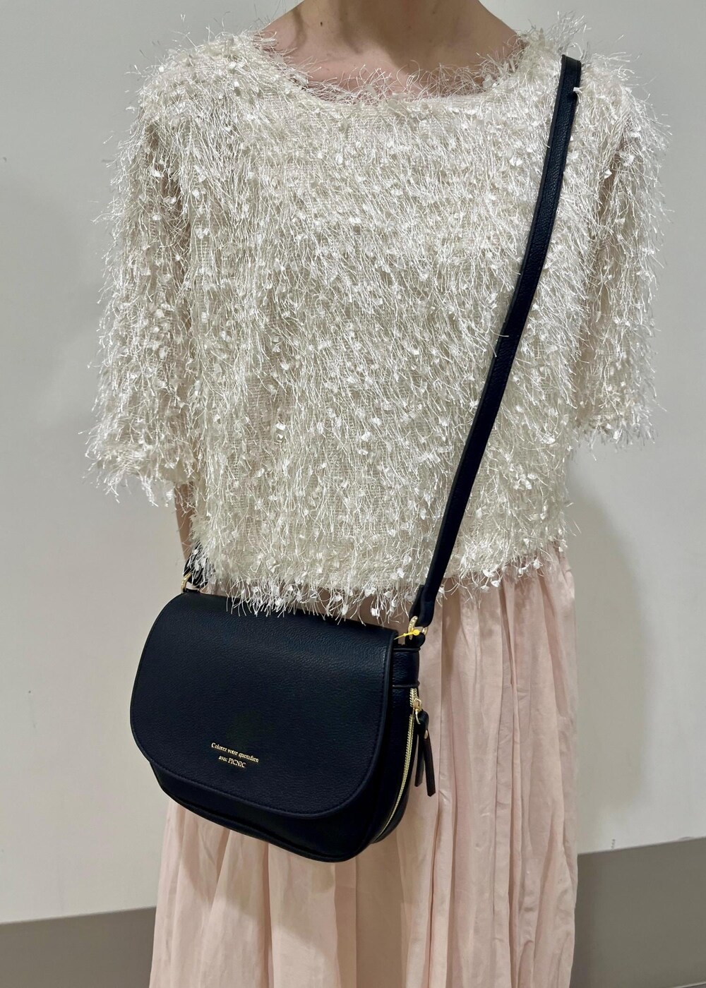 ブラック系のパンプス、ホワイト系のスカート、ブラック系のショルダーバッグを着用したレディースの春コーディネートの4枚目の写真