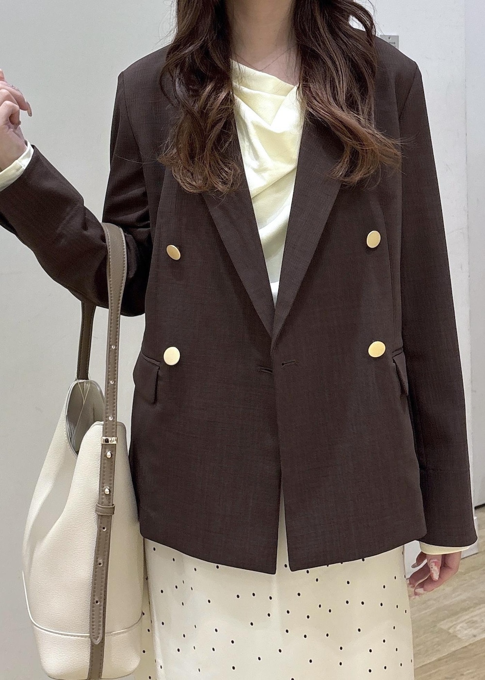 ホワイト系のショルダーバッグ、ベージュ系のTシャツ/カットソー、ブラウン系のテーラードジャケットを着用したレディースの春コーディネートの5枚目の写真