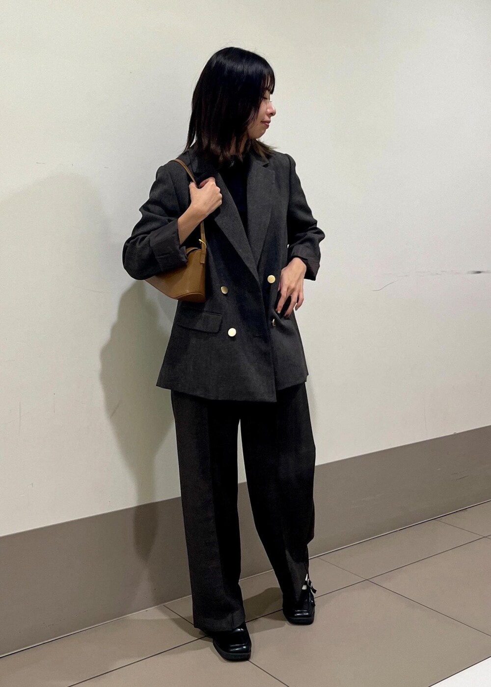 ブラック系のニット/セーター、ブラウン系のテーラードジャケット、ブラウン系のショルダーバッグを着用したレディースの秋コーディネートの2枚目の写真