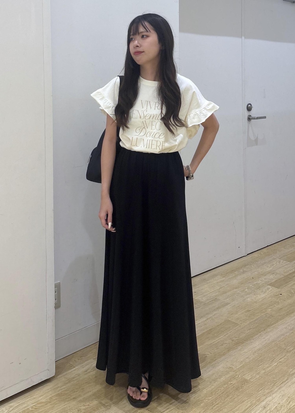 ブラック系のサンダル、ホワイト系のTシャツ/カットソー、ブラック系のスカートを着用したレディースの夏コーディネートの2枚目の写真