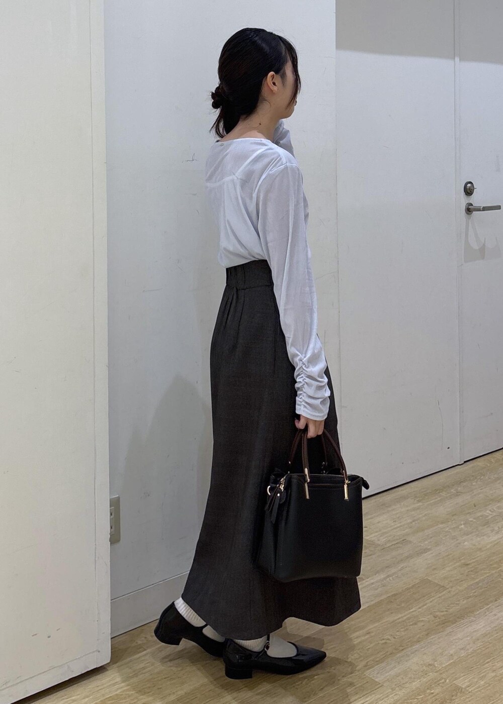 ブラック系のパンプス、ブラック系のトートバッグ、ブラウン系のスカートを着用したレディースの秋コーディネートの3枚目の写真