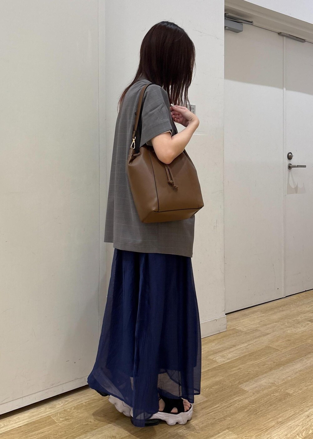 グレー系のテーラードジャケット、ブラウン系のショルダーバッグ、ブルー系のスカートを着用したレディースの夏コーディネートの3枚目の写真