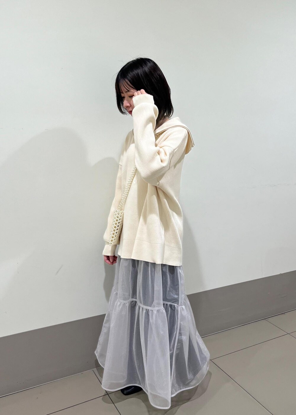 ホワイト系のショルダーバッグ、ブルー系のデニムパンツ、グレー系のスカートを着用したレディースの春コーディネートの3枚目の写真